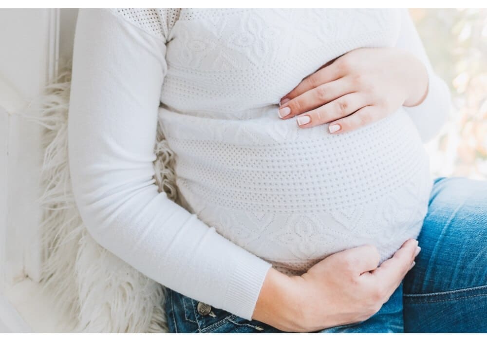 Imagen de una mujer embarazada con las manos en la parte superior e inferior de su vientre